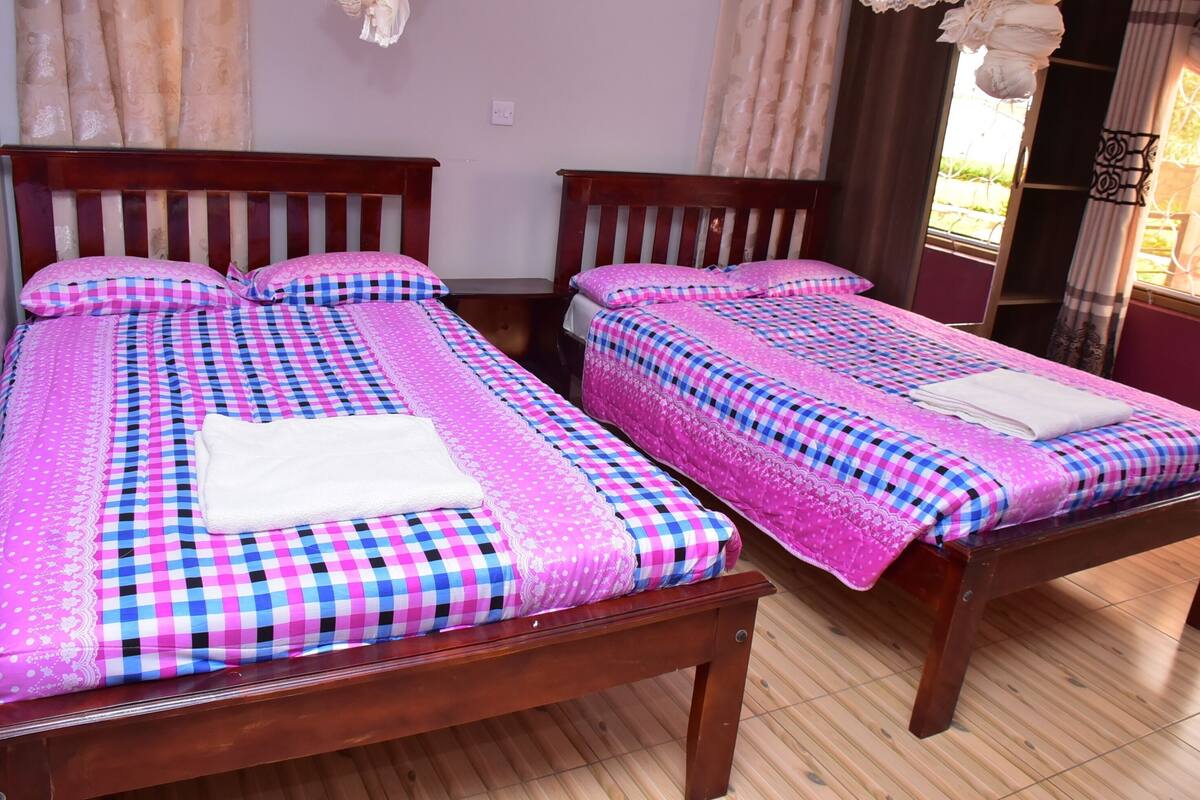 Dos camas de madera con ropa de cama a cuadros y almohadas blancas.
