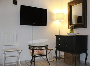 Relax in a compact room with a flat-screen TV, a small table, and a comfortable chair.