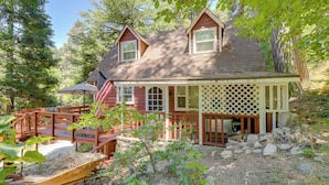 A two-story house with a porch, a wooden deck, and a small garden area. - Vintage 'Snow White' Cottage ~ 2 Miles to Village! (Lake Arrowhead)