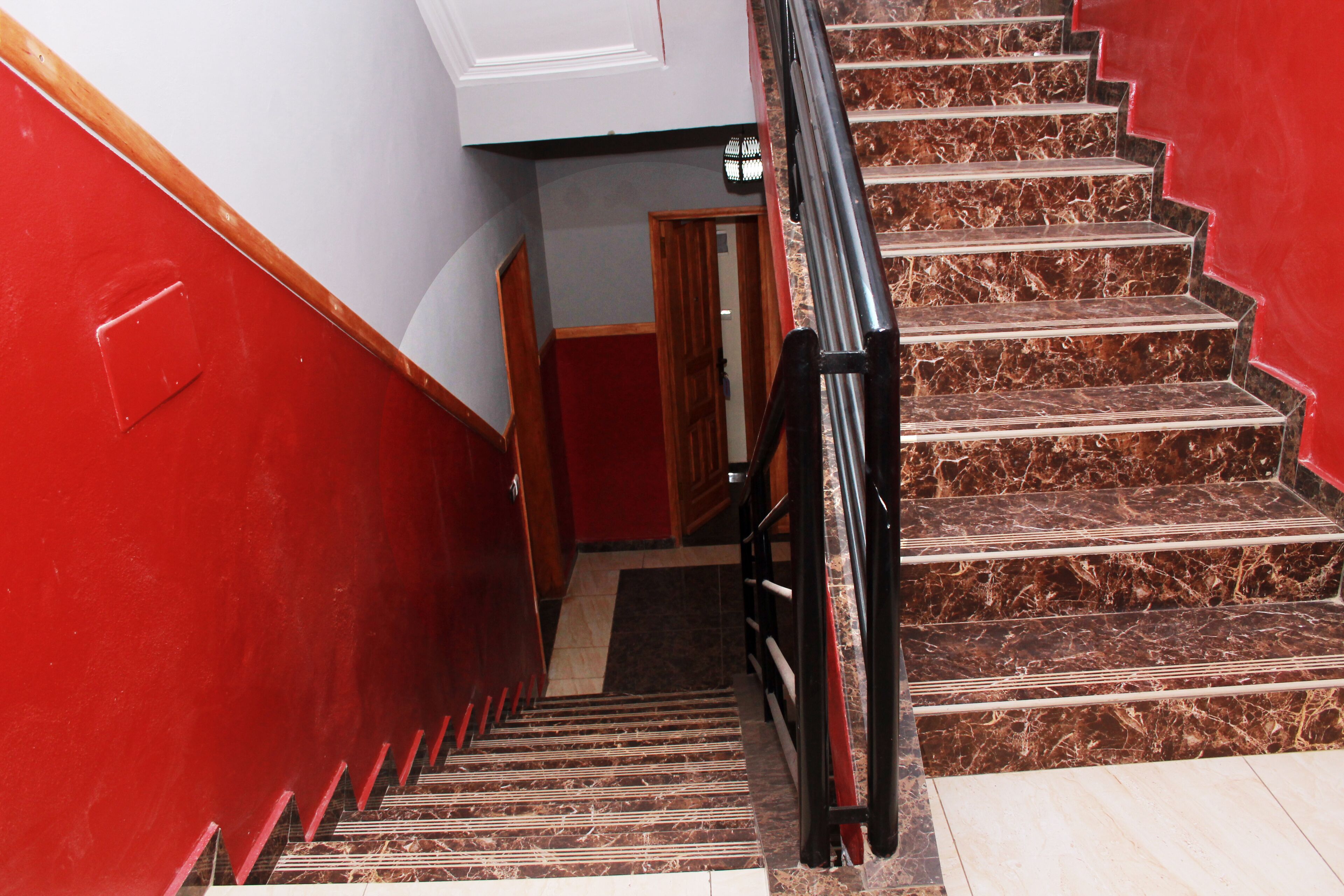 Una escalera con paredes rojas y escalones de mármol.