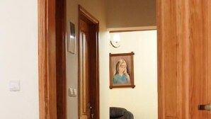 A hallway with a bed at the end, a door, a framed picture on the wall, and a leather chair. - Deutch' Lodges (Yaoundé)
