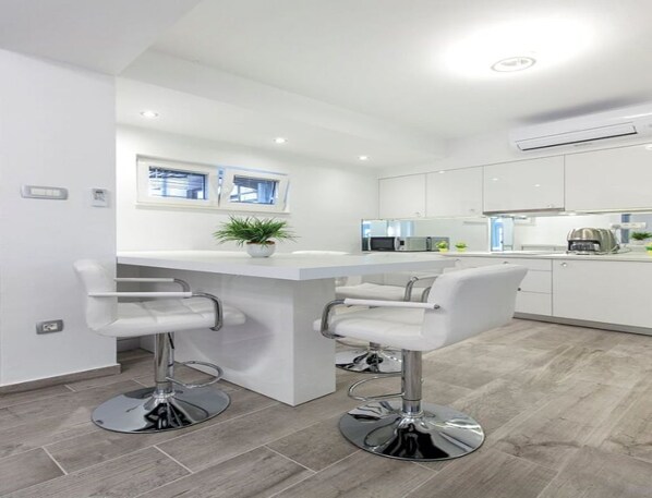 A modern kitchen with white cabinets, a central island with bar stools, and a window above the sink.
