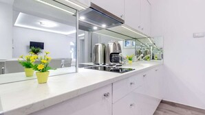 Una cocina moderna con un espejo grande, electrodomésticos de acero inoxidable y plantas en macetas.