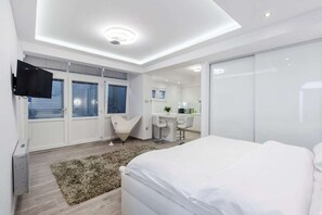 A modern bedroom with a large bed, a desk, and a chair.