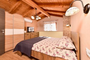 A bedroom with a bed, wooden wardrobe, television, and a hanging light fixture. - House 2014/28564 (Istria - Žminj), 30000m from the beach (Žminj)