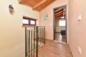 A wooden staircase with a metal railing leading to a bedroom with a bed and a window.
