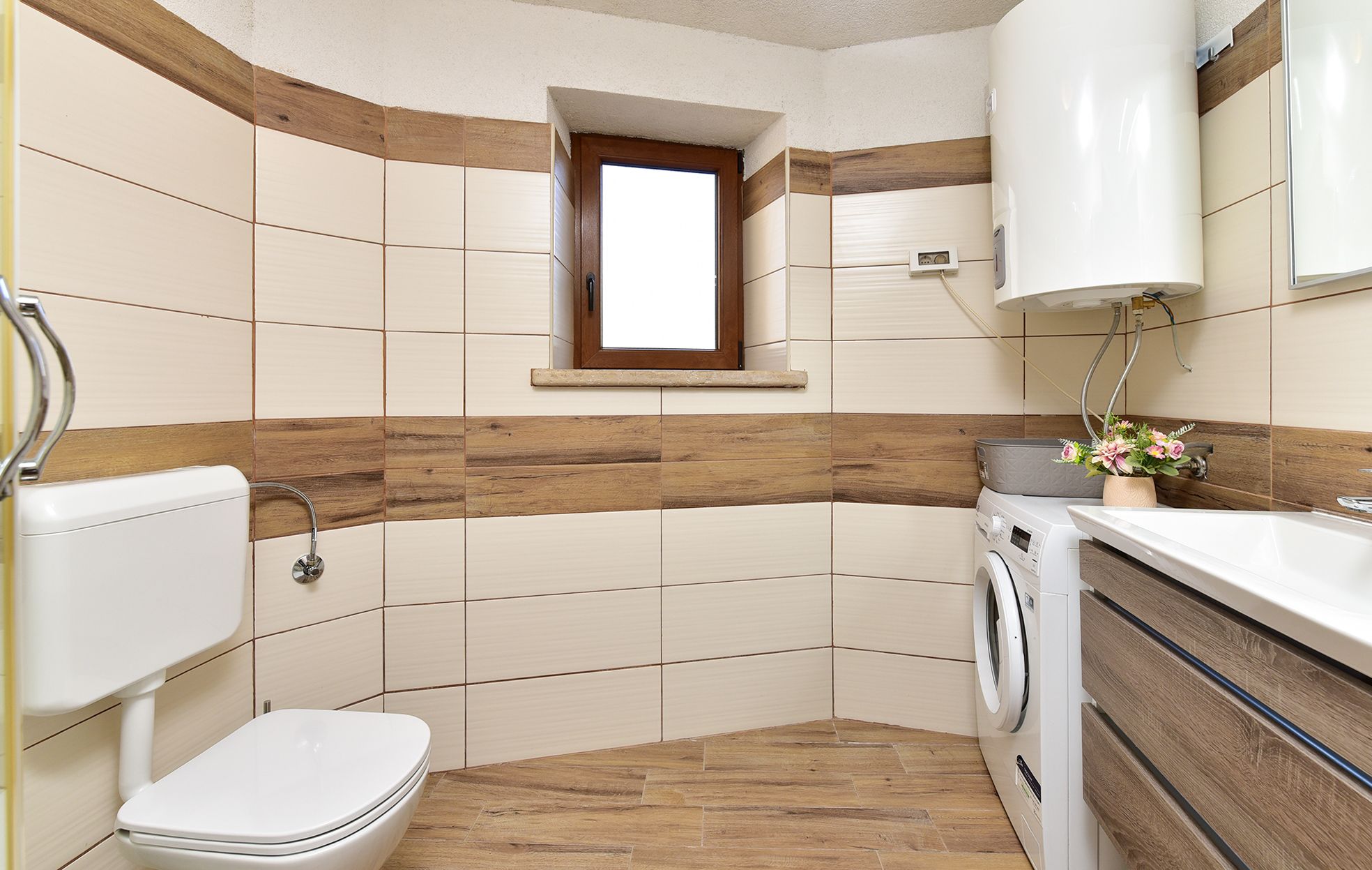 A compact bathroom with a toilet, washing machine, and a small window.