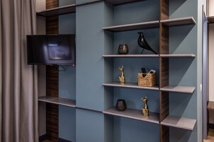 Un interior moderno con un televisor de pantalla plana montado en la pared, rodeado de estantes con objetos decorativos.