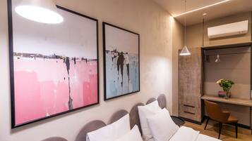 A modern hotel room with a bed, a desk, and two large abstract paintings on the wall.