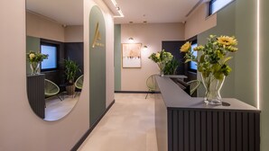 A modern reception area with a desk, chairs, and a mirror. - Allure Boutique Hotel (Tirana)