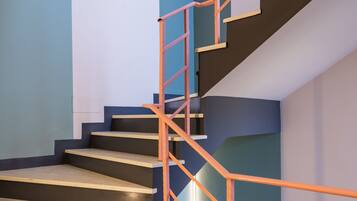 Una escalera de diseño moderno, con una combinación de peldaños oscuros y claros y una barandilla de metal.