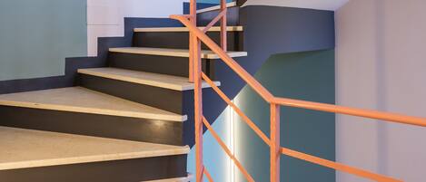 Una escalera de diseño moderno, con una combinación de peldaños oscuros y claros y una barandilla de metal.