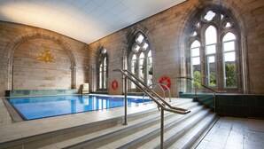 Une piscine intérieure avec des arches en pierre, une bouée de sauvetage et une chaise.