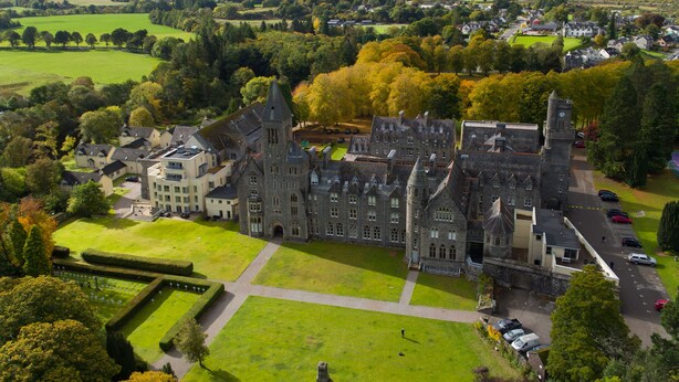 Un grand bâtiment historique doté de nombreuses tours et d’une pelouse bien entretenue.