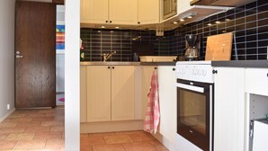 Una cocina con armarios blancos, un salpicadero de baldosas negras, una cafetera y una estufa.