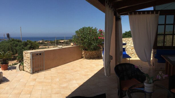 A terrace with a view of the sea, a stone wall, and a potted plant. - Lampedusa catatteristic dammuso sea view, 200mt distant, 180° (Lampedusa)