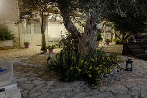 A courtyard with a tree, potted plants, and outdoor seating.