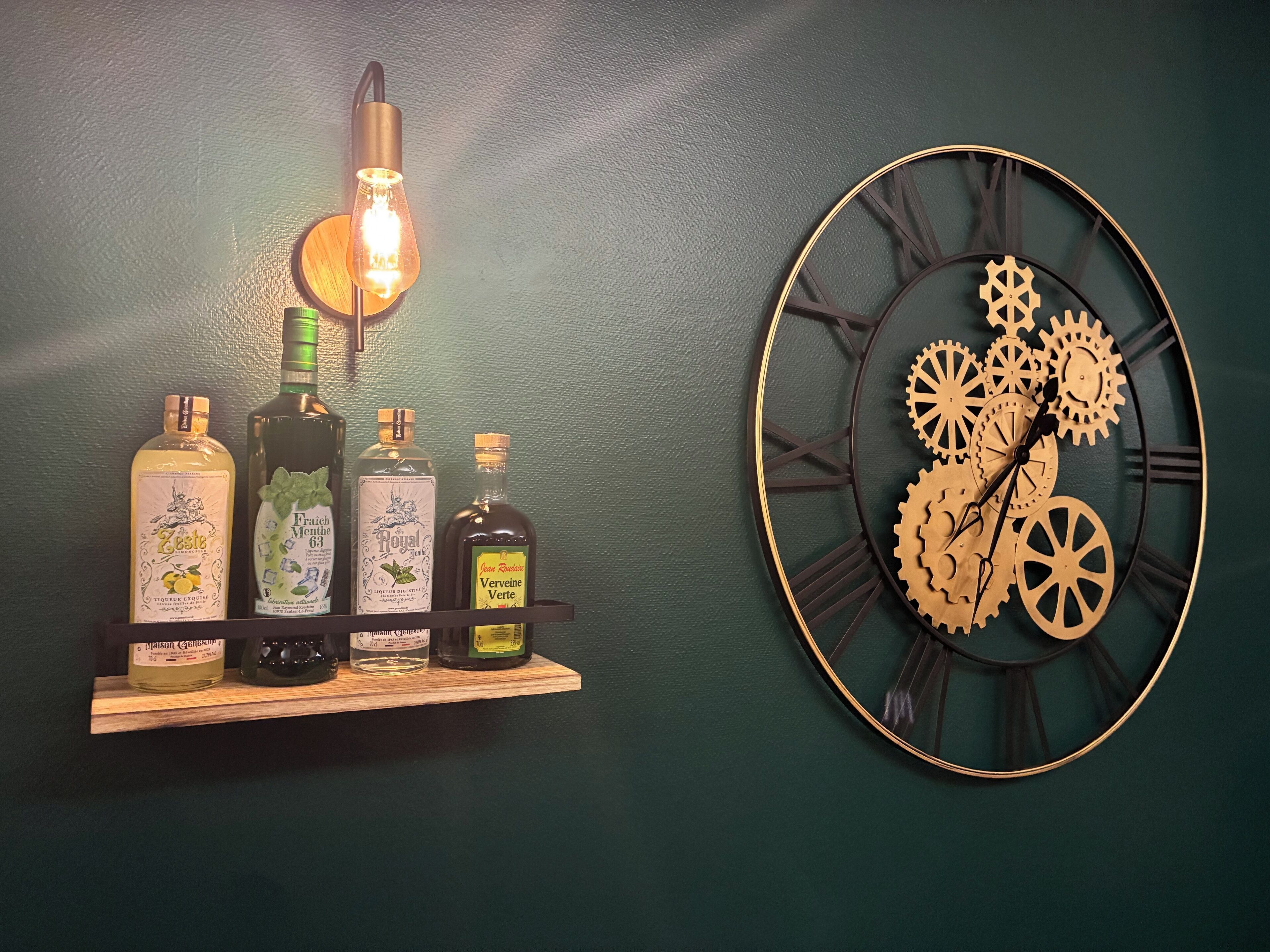 A wall-mounted clock with Roman numerals and gears, and a shelf with various bottles of liquor.