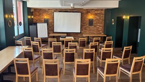 A conference room with a large table, multiple chairs, a projector screen, and a wooden wall with a suggestion board. - Hotel du Commerce (Volvic)