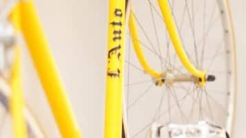 Un vélo jaune avec un cadre blanc et un panier à l’avant, fixé au mur.