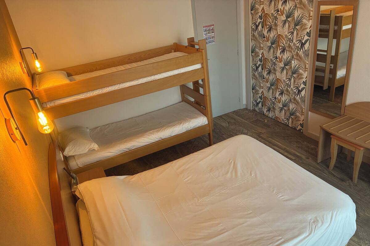A bunk bed with a wooden headboard, a bedside table, and a lamp.