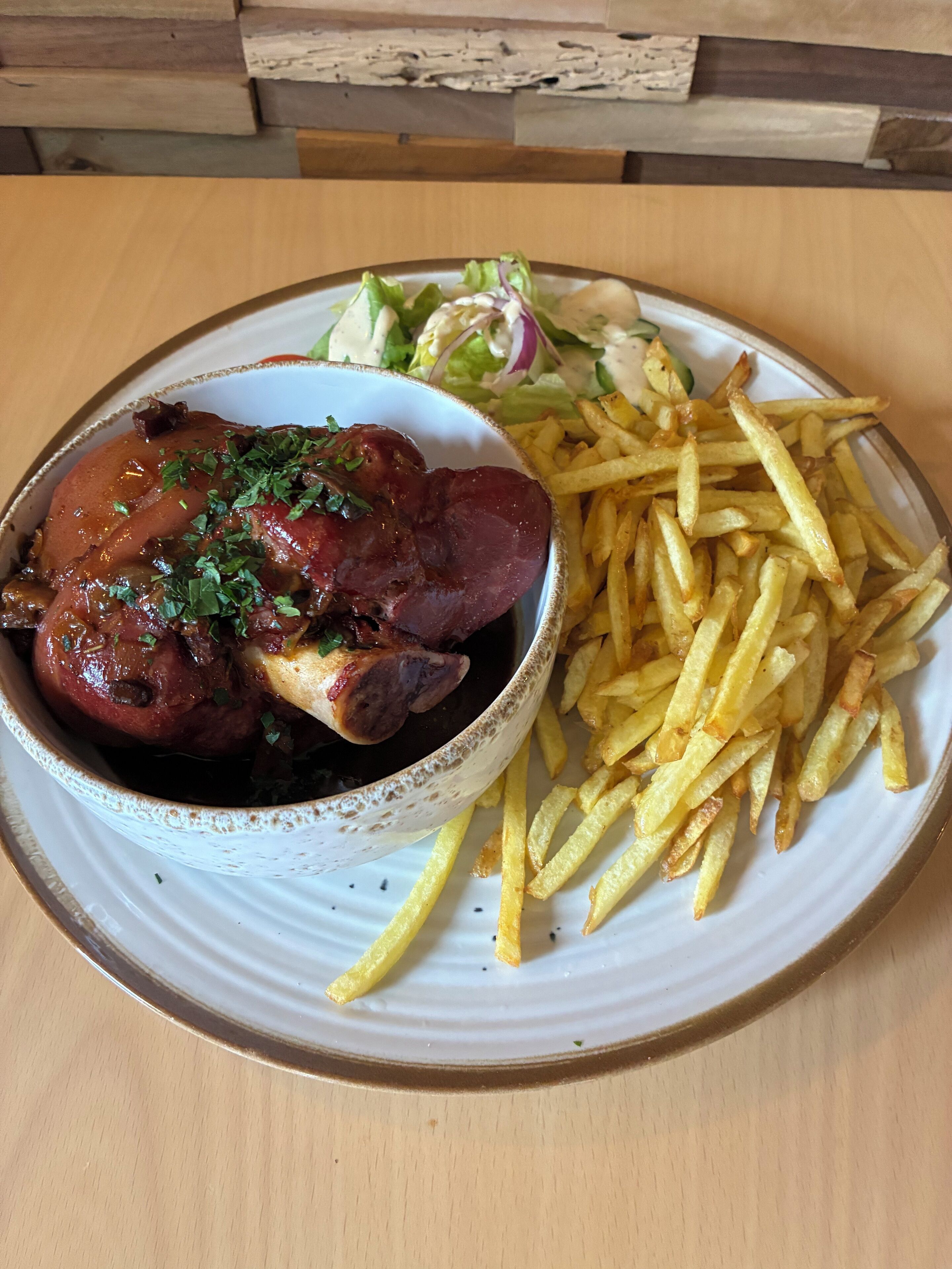 En tallerken med kød, pommes frites og en salat.