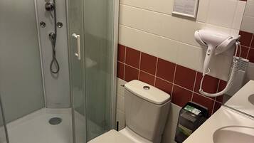 A bathroom with a glass-enclosed shower, a toilet, and a sink.