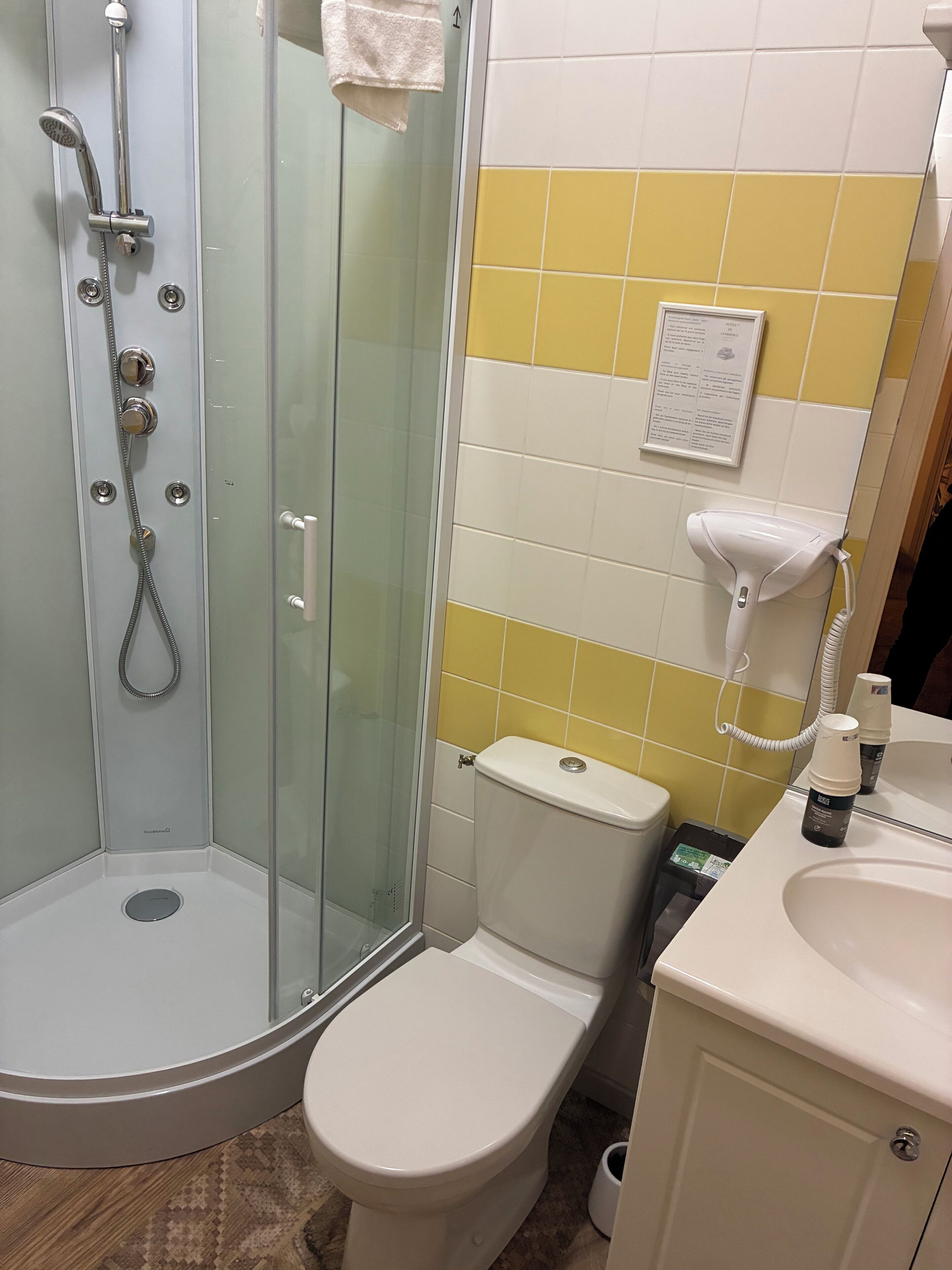 A bathroom with a glass-enclosed shower, a toilet, and a sink.