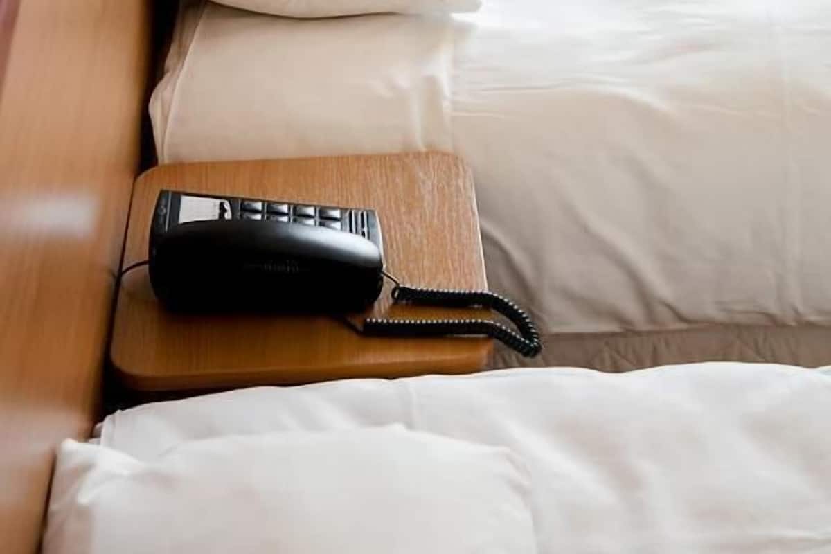 A hotel room with a wooden headboard, a desk, and a chair.