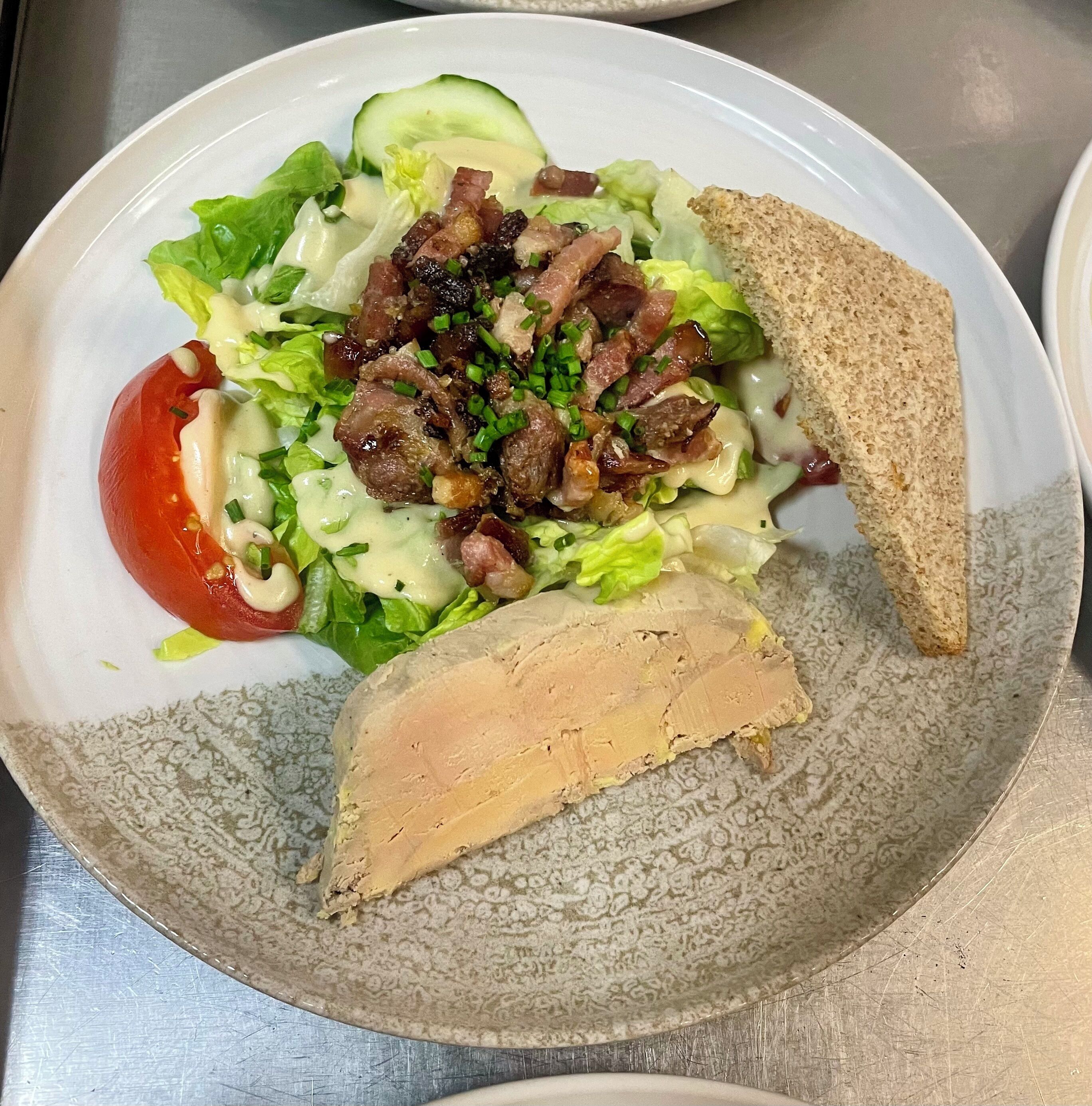 Un plato con ensalada, una rebanada de pan y un trozo de carne.