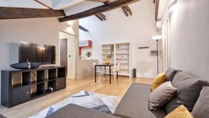 A modern living room with a sofa, TV, and built-in shelving. - GuestHost - Cozy and modern flat 80sqm with all the comfort, convenient for its position in the city center of Turin, very close to the main points of interest of the city as the Egyptian Museum, only 500m away, Piazza Solferino (400m), and Giardini Real (Torino)