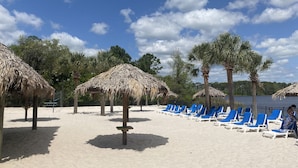 Une plage avec des parasols en chaume et des chaises longues bleues.