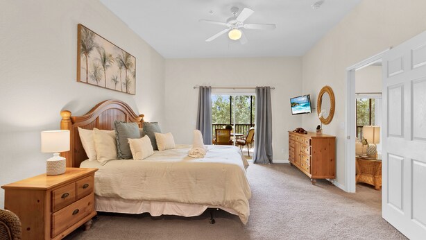 Une chambre à coucher avec un lit, une table de chevet, une commode et un téléviseur fixé au mur.