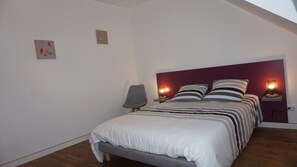 Une chambre à coucher comprenant un lit, deux lampes de chevet, une chaise et deux œuvres d’art murales.