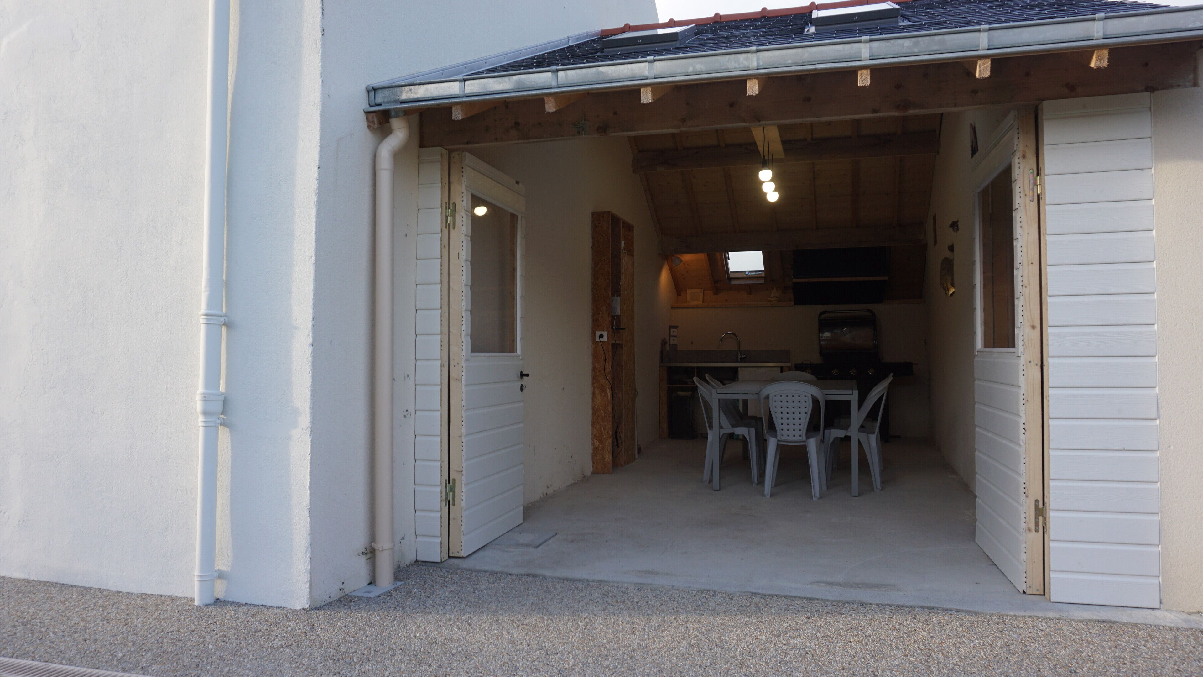 A covered outdoor area with a table and chairs, a grill, and a television.