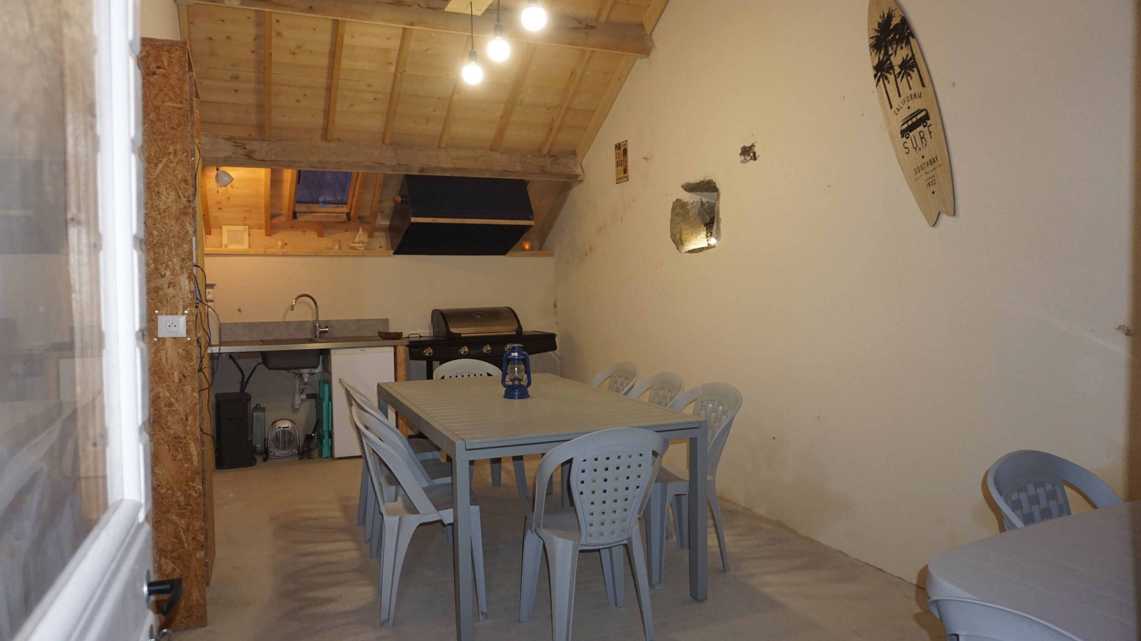 Een kleine keuken met een eethoek, houten plafond en een surfboard decoratie.