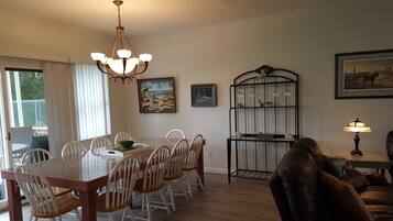 A dining area with a table, chairs, a chandelier, and artwork on the walls.