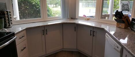 A kitchen with white cabinets, a granite countertop, and a dishwasher.