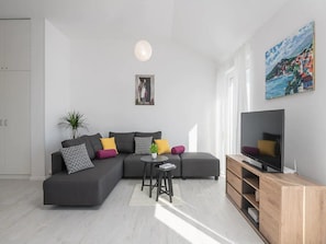 Relax in this stylish living room with a grey sofa, flat-screen TV, and a cozy reading nook.