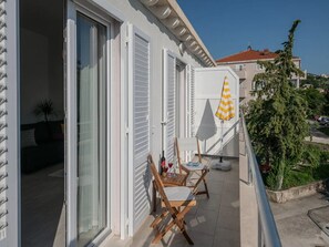 Enjoy the serene view of the neighborhood from this balcony with a comfortable seating area.