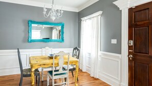A dining room with a wooden table, chairs, a chandelier, and a large mirror on the wall.