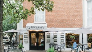 A plant-based cafe with outdoor seating and a brick building facade.