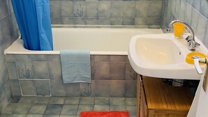A bathroom with a bathtub, a sink, and a shower curtain. - RENTAL HOUSE IN PEACE (Sibiril)