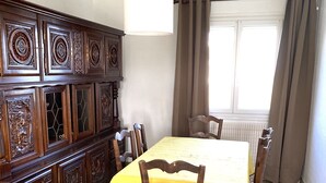 A dining area with a wooden cabinet, a table with a yellow tablecloth, and chairs. - RENTAL HOUSE IN PEACE (Sibiril)