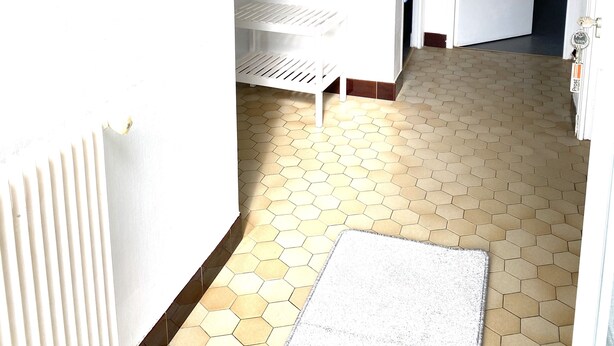 A hallway with a white radiator, a mirror with a sunburst frame, a white shelf, and a hexagonal tiled floor. - RENTAL HOUSE IN PEACE (Sibiril)