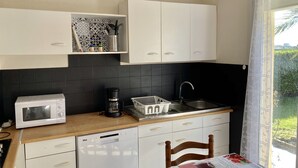 A compact kitchen with white cabinets, a microwave, a coffee maker, and a dishwasher. - RENTAL HOUSE IN PEACE (Sibiril)