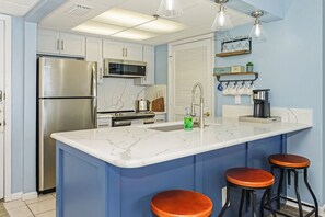 A kitchen with a large island, stainless steel appliances, and bar stools. - MOST BEAUTIFUL LONG BEACH CONDO! COMPLETE RENOVATION! (Panama City Beach)