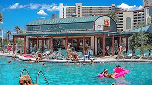 Un espace piscine avec des chaises longues et un coin salon abrité.