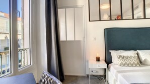 Une chambre d’hôtel avec un lit, une table de chevet et une vue sur la ville par la fenêtre.