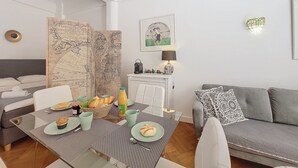 Una sala de estar moderna con zona de comedor, que incluye un mapa giratorio, una lámpara y un sofá con cojines estampados.